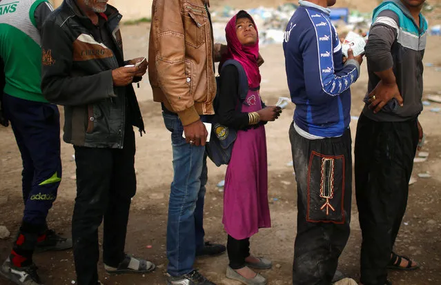 Displaced Iraqis wait to get food supplies as Iraqi forces battle with Islamic State militants, in western Mosul, Iraq March 27, 2017. (Photo by Suhaib Salem/Reuters)