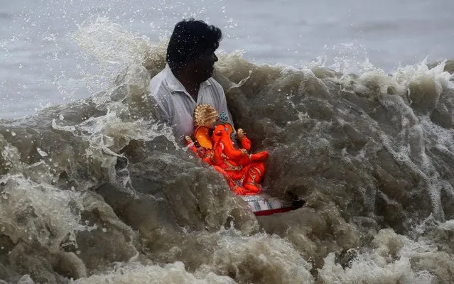 An Indian Hindu devotee carries an idol of elephant-headed Hindu god Ganesha for immersing it in the Arabian Sea on the fifth day of the ten-day long Ganesh Chaturthi festival in Mumbai, India, Friday, September 6, 2019. The festival is a celebration of the birth of Ganesha, the Hindu god of wisdom, prosperity and good fortune. (Photo by Rajanish Kakade/AP Photo)