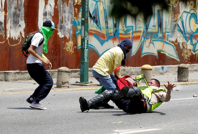 Demonstrators grab a riot police officer at a rally against Venezuela's President Nicolas Maduro's government in Caracas, Venezuela April 10, 2017. (Photo by Christian Veron/Reuters)