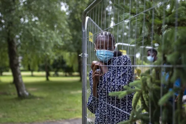 Neosanhare Esone Queen, a migrant from Nigeria, looks though a fence at the refugee camp in the village of Verebiejai, Lithuania, Sunday, July 11, 2021. The European Union's border agency is pledging to “significantly” step up its support to Lithuania “due to the growing migratory pressure at Lithuania's border with Belarus” that the Baltic nation is trying to contain. Lithuania's interior minister said late Friday that the decision, proposed by the State Border Guard Service, was necessary not because of increased threats to the country of 2.8 million but to put a more robust system in place to handle migrants. (Photo by Mindaugas Kulbis/AP Photo)