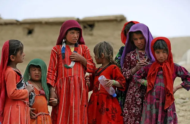In this Sunday, May 4, 2014 photo, Survivors wait for donations near the site of Friday's landslide that buried Abi-Barik village in Badakhshan province, northeastern Afghanistan. Stranded and with no homes, many of the families have struggled to get aid. Some have gone to nearby villages to stay with relatives or friends, while others have slept in tents provided by aid groups. The unlucky ones have slept outside. (Photo by Massoud Hossaini/AP Photo)