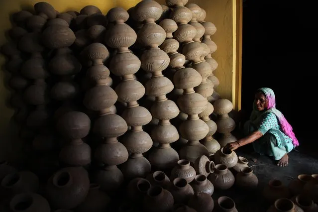 An Indian potter stacks earthen pots as she stores them in her house after making them on the outskirts of Jammu, India, Tuesday, May 10, 2016. The earthen pots are used to store water cool and are in demand during summer. (Photo by Channi Anand/AP Photo)