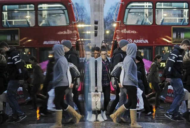 Shoppers are reflected in a shop window as they walk along Oxford Street on the last Saturday before Christmas, in London in this December 21, 2013 file photo. (Photo by Luke MacGregor/Reuters)