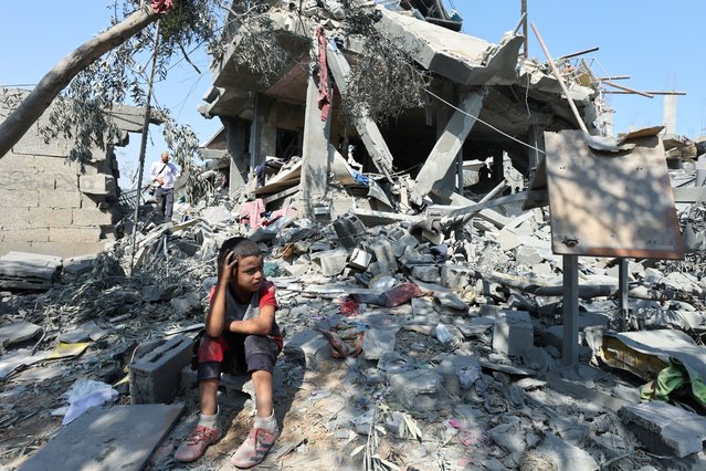 A child sits amid the rubble as Palestinians inspect a house destroyed in an Israeli strike, amid the Israel-Hamas conflict, in Nusairat refuge camp, in the central Gaza Strip, on July 9, 2024. (Photo by Ramadan Abed/Reuters)