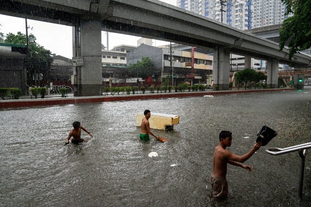 Men wade through a flooded road following heavy rains brought by Typhoon Gaemi, in Manila, Philippines, on July 24, 2024. (Photo by Lisa Marie David/Reuters)