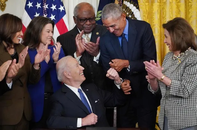 US President Joe Biden (3rd L) bumps fists with  former president Barack Obama (2nd R) while signing an executive order intended to strengthen the Affordable Care Act, after delivering remarks in the East Room of the White House in Washington, DC, on April 5, 2022. Also pictured (from L) US Vice President Kamala Harris, US Representative Angie Craig (D-MN), US Representative James Clyburn (D-SC), and US House Speaker Nancy Pelosi (D-CA). (Photo by Mandel Ngan/AFP Photo)