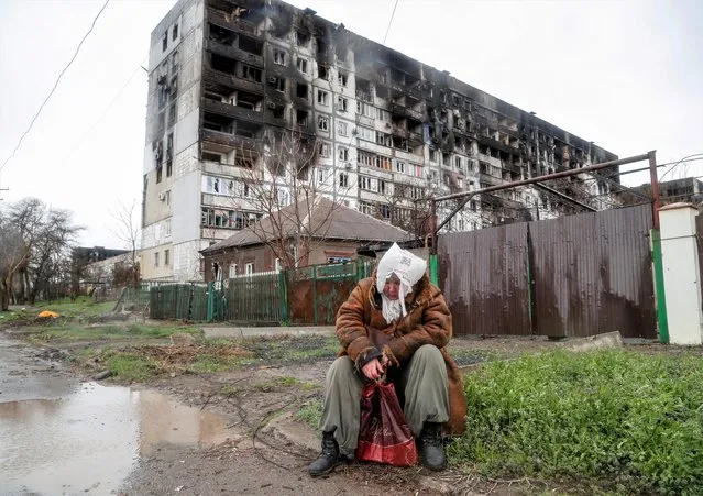 A woman sits in front of a residential building damaged in the course of Ukraine-Russia conflict, on a rainy day in the southern port city of Mariupol, Ukraine on April 13, 2022. (Photo by Alexander Ermochenko/Reuters)