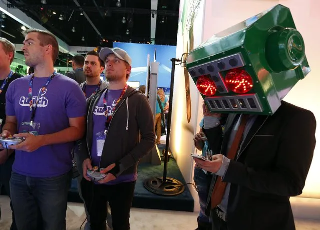 A man dressed as Mr. Destructoid checks his mobile phone while gamers play a game at the 2014 Electronic Entertainment Expo, known as E3, in Los Angeles, June 10, 2014.  REUTERS/Jonathan Alcorn