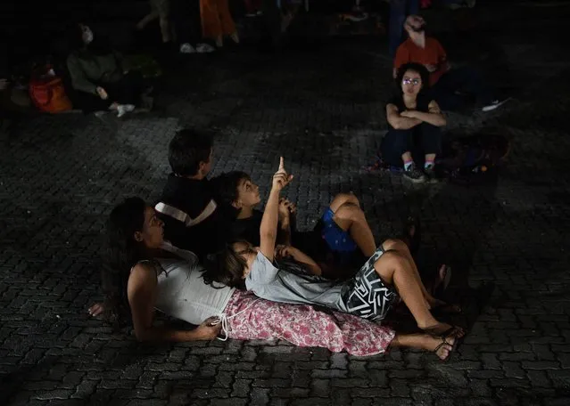 People watch a blood moon during a total lunar eclipse in Rio de Janeiro on May 16, 2022. (Photo by Carl de Souza/AFP Photo) 