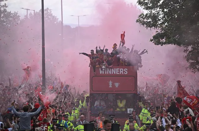 Liverpool's players celebrate from an open-top bus with supporters during a parade through the streets of Liverpool in north-west England on May 29, 2022, to celebrate winning the 2021-22 League Cup and FA Cup. Despite the disappointment of losing to real Madrid in the final of the UEAF Champions League, Klopp has called on Liverpool fans to take to the streets of the city on Sunday when they parade the League Cup and FA Cup. (Photo by Oli Scarff/AFP Photo)