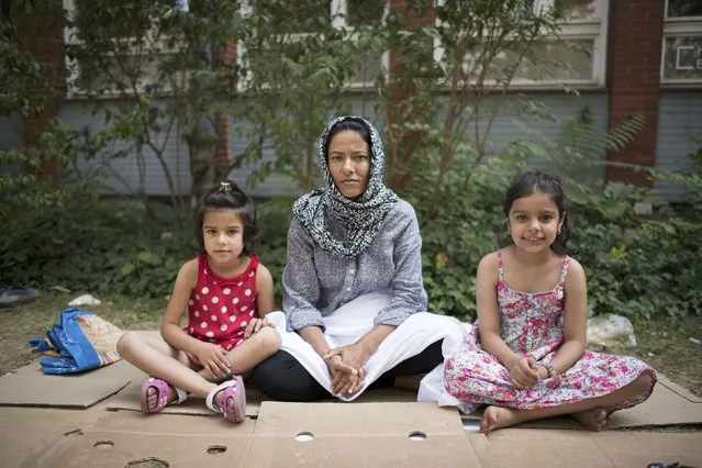 Syrian migrant Hanife (C) and her daughters Roya, 7, and Fatima, 6, (R) sit on the ground in front of the State Office for Health and Social Affairs as they wait to apply for asylum in Berlin, Germany August 10, 2015. (Photo by Stefanie Loos/Reuters)