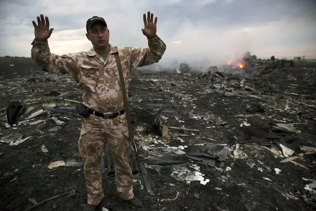A man gestures at a crash site of a passenger plane near the village of Grabovo, Ukraine, Thursday, July 17, 2014. Ukraine said a passenger plane carrying 295 people was shot down Thursday as it flew over the country, and both the government and the pro-Russia separatists fighting in the region denied any responsibility for downing the plane. (Photo by Dmitry Lovetsky/AP Photo)