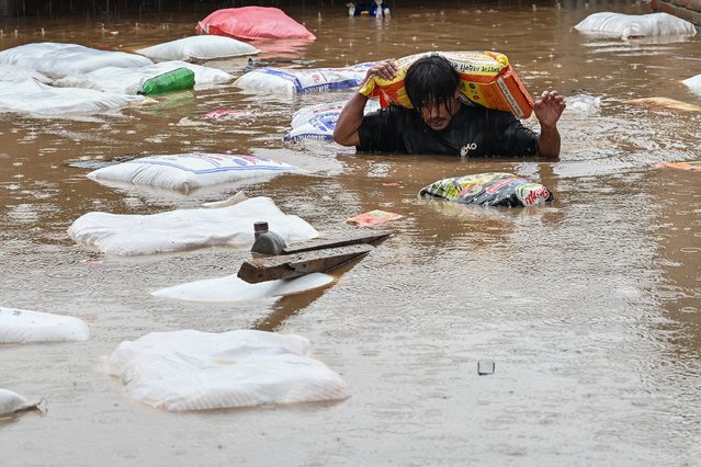 A man carrying a sack of flour wades through flood waters after the Bagmati River overflowed following heavy monsoon rains in Kathmandu on September 28, 2024. Floods and landslides caused by heavy downpours in Nepal killed at least 10 people across the Himalayan country, with rescue teams searching for 18 missing, a disaster official said on September 28. (Photo by Prakash Mathema/AFP Photo)