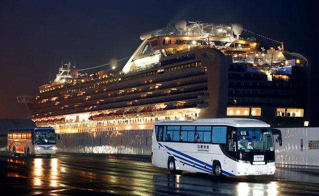 Buses carrying U.S. passengers who were aboard the quarantined cruise ship the Diamond Princess, seen in background, leaves Yokohama port, near Tokyo, early Monday, February 17, 2020. The cruise ship was carrying nearly 3,500 passengers and crew members under quarantine. (Photo by Jun Hirata/Kyodo News via AP Photo)