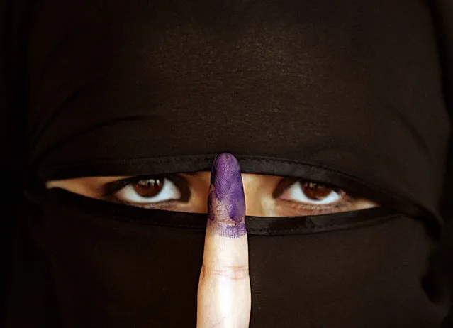 An Iraqi Sunni woman shows her ink-stained finger after casting her  vote in Amman December 15, 2005