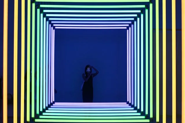 A woman uses her mobile phone to take a picture of “Spectrum” by Olivier Ratsi as she visits an exhibition at a museum in Beijing on July 22, 2022. (Photo by Zhao Wang/AFP Photo)