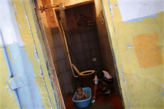 A baby takes a bath as his relative holds a bar of soap as they occupy an empty building in an area of Sao Paulo's Luz neighborhood known to locals as Cracolandia (Crackland),  August 12, 2015. (Photo by Nacho Doce/Reuters)