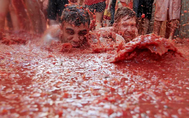 Two men lie in a puddle of squashed tomatoes, during the annual “Tomatina” tomato fight fiesta, in the village of Bunol, 50 kilometers outside Valencia, Spain, Wednesday, August 26, 2015. (Photo by Alberto Saiz/AP Phot)