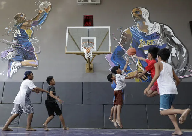 Boys plays beside images of former NBA basketball player Kobe Bryant at the “House of Kobe” basketball court in Valenzuela, north of Manila, Philippines on Monday, January 27, 2020. Fans left flowers and messages on the walls at the newly inaugurated court after learning of Bryant's death. Bryant died in a helicopter crash. (Photo by Aaron Favila/AP Photo)