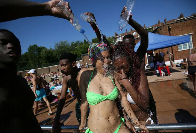 People splash water on each other as they pose for the camera at Parliament Hill Lido on a sunny day in London, Britain July 19, 2016. (Photo by Neil Hall/Reuters)