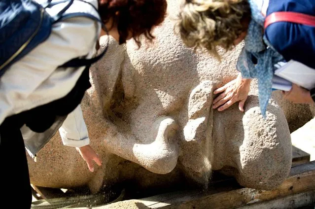 Two employees remove sand from the beard and the eyes of the giant Lenin head in Berlin, Germany, Thursday September 10, 2015. The 3,900-kilogram (8,600-pound) head of Vladimir Lenin that was removed from a Berlin square in 1991 has been unearthed for a new exhibition. (Photo by Gregor Fischer/DPA via AP Photo)