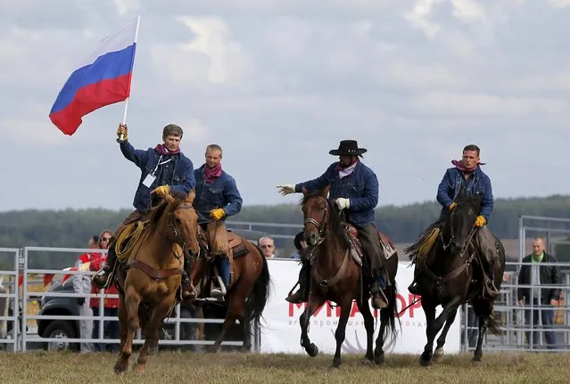 A participant rides with the Russian national flag before the start of the Russian Rodeo in the village of Kotliakovo, Bryansk region, southeast of Moscow, Russia, September 12, 2015. The competition was organised by privately held Miratorg, one of the leading Russia's meat producers, between the divisions of the agricultural holding. (Photo by Maxim Shemetov/Reuters)