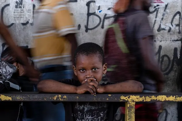 A child looks on as people walk past in Port-au-Prince, Haiti on October 12, 2022. (Photo by Ricardo Arduengo/Reuters)