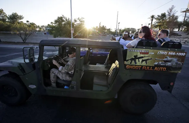In this Tuesday, October 3, 2017 photo, tourists get a ride in a tour vehicle that also advertises gun range activities in Las Vegas. A gunman opened fire on an outdoor music concert on Sunday making it the deadliest mass shooting in modern U.S. history. But even though the city is in mourning, for many it is business as usual with celebrations and parties continuing. (Photo by Chris Carlson/AP Photo)