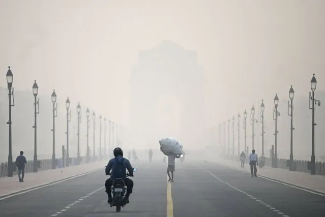 A man carries a sack along the road in front of India Gate amid smoggy conditions in New Delhi on November 1, 2022. (Photo by Money Sharma/AFP Photo)