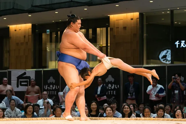 A sumo wrestler plays with a child during an exhibition before the start of a special grand sumo tournament in Tokyo, Japan on August 29, 2016. (Photo by Aflo/Barcroft Images)