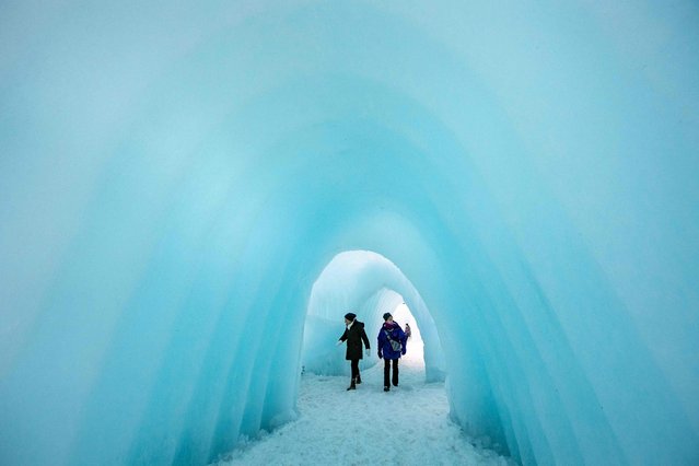 People explore the ice walls, trails and caverns at Ice Castles in North Woodstock, New Hampshire on February 1, 2024. Founder Brent Christensen, crafted his first icy creation in the front yard of his home to bring happiness and joy to his children. Since 2011, Ice Castles has been dedicated to creating a world of ice caves, frozen waterfalls, and glaciers formed into archways, caverns, slides, and tunnels. (Photo by Joseph Prezioso/AFP Photo)