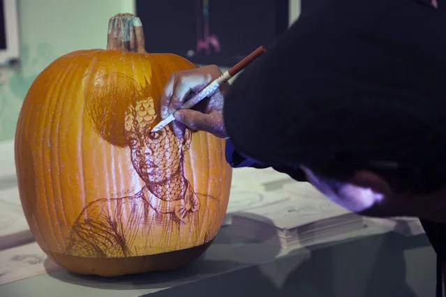 Chris Soria of the Maniac Pumpkin Carvers demonstrates how to apply a stencil on to a pumpkin by using a digital projector at Cotton Candy Machine in Brooklyn, N.Y. on October 18, 2014. (Photo by Siemond Chan/Yahoo Finance)
