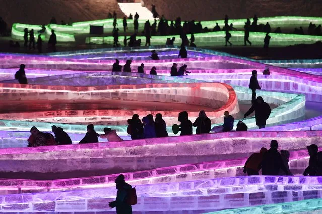 Visitors walk and slide on icy paths on the opening day of the annual Harbin Ice and Snow Sculpture Festival in Harbin, in China's northeast Heilongjiang province on January 5, 2018. The festival, featuring dozens of huge ice sculptures lit up by coloured lights, attracts hundreds of thousands of visitors annually. (Photo by Greg Baker/AFP Photo)