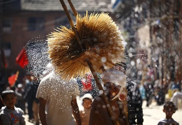 A man portraying the Hindu God Madhav Narayan splashes water towards devotees as he walks around town during the Madhav Narayan Festival in Thecho, near Kathmandu, February 22, 2013. The month-long festival dedicated to the Hindu deities Madhav Narayan and Swasthani involves the recitation of folk tales about miraculous feats performed by them in many Hindu households. (Photo by Navesh Chitrakar/Reuters)