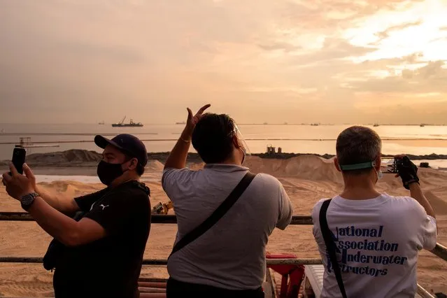 Locals take pictures from a footbridge overlooking the construction of the Manila Bay beach, where artificial sand or crushed dolomite were dumped as part of the government's efforts to rehabilitate and beautify the polluted coastline, in Manila, Philippines, September 10, 2020. (Photo by Eloisa Lopez/Reuters)