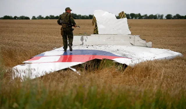 An armed pro-Russian separatist stands on part of the wreckage of the Malaysia Airlines Boeing 777 plane after it crashed near the settlement of Grabovo in the Donetsk region, July 17, 2014. (Photo by Maxim Zmeyev/Reuters)