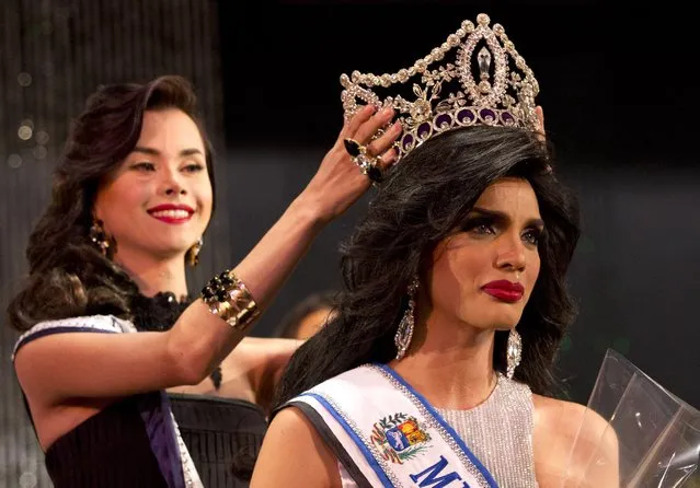 In this October 18, 2015 photo, Argenis Gonzalez, 24, is crowned Miss Gay Venezuela by last year's winner Sandro Porras in Caracas, Venezuela. The jeweled crown was designed by Gorge Wittels, who also designs the crowns for Miss Venezuela. When not dressed as a woman, Gonzalez, a social media coordinator, goes by the name Manuel. (Photo by Ariana Cubillos/AP Photo)