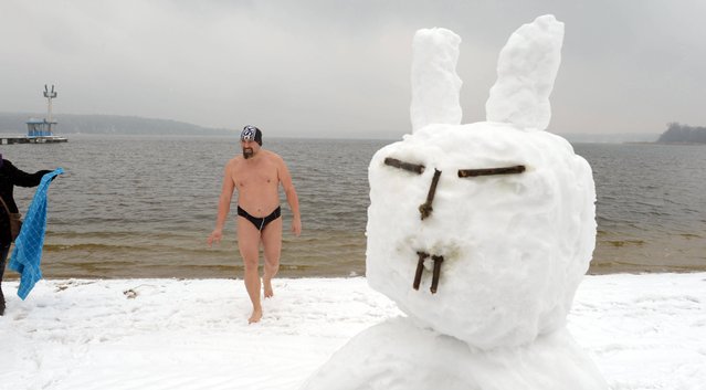 A swimmer gets  out of the water next to a snowman with bunny ears at the snow covered beach of  Strandbad  Lake Wannsee lido  in Berlin, Germany,  Good Friday March 29, 2013.  Bathing season at the lido traditionally starts on Good Friday. (Photo by Rainer Jensen/AP Photo/Dpa)