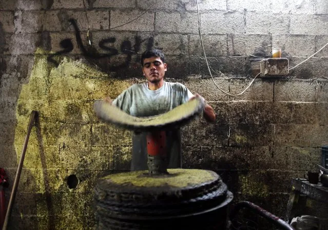 A Palestinian man carries a sheet of ground olives to be made into oil at an olive press in Gaza City October 4, 2016. (Photo by Mohammed Salem/Reuters)