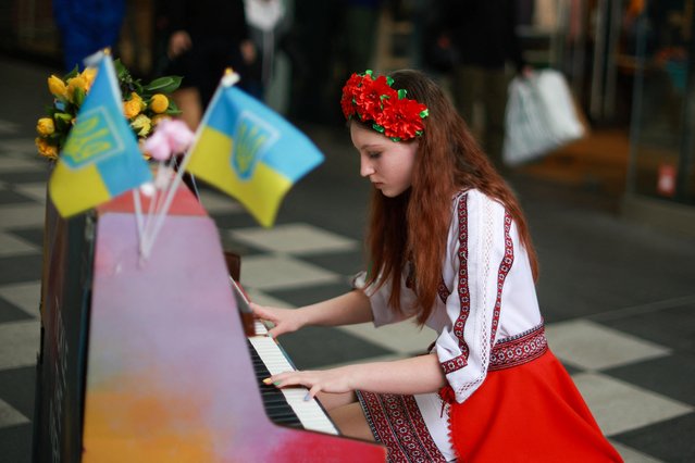 13-year old Alisa Bushuieva, who was forced to flee Ukraine at the start of the war, wears a Ukrainian national dress as she plays the piano at an event to mark the first anniversary of Russia's invasion of Ukraine in Liverpool, Britain on February 24, 2023. (Photo by Phil Noble/Reuters)