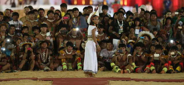 In this October 24, 2015 photo, indigenous men take photos of a Pataxo indigenous woman from Brazil during a "parade of indigenous beauty" at the World Indigenous Games in Palmas, Brazil. The Indigenous Games organizers stressed it wasn't a beauty contest - no queen was crowned, no runners-up selected.  It was, they insisted, a celebration of facial features, body types and adornments not often given their due. (Photo by Eraldo Peres/AP Photo)
