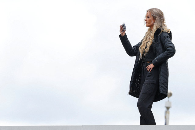 Conservative social-media influencers Katie Daviscourt uses a smartphone as she watches protesters from a deck at an ICE facility in Portland, Oregon, U.S., October 4, 2025. (Photo by Carlos Barria/Reuters)