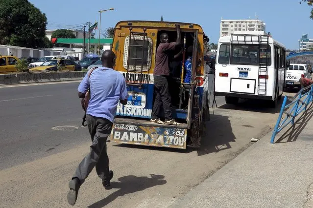 A man runs to catch a ride on a "car rapide" in Dakar, Senegal, October 29, 2015. The colorful mini-buses that roam the streets of the Senegalese capital of Dakar have gained such fame over their forty years that, more than 4,000 km (2,485 miles) away, an exhibit devoted to them is on display at the Museum of Mankind in Paris. (Photo by Makini Brice/Reuters)