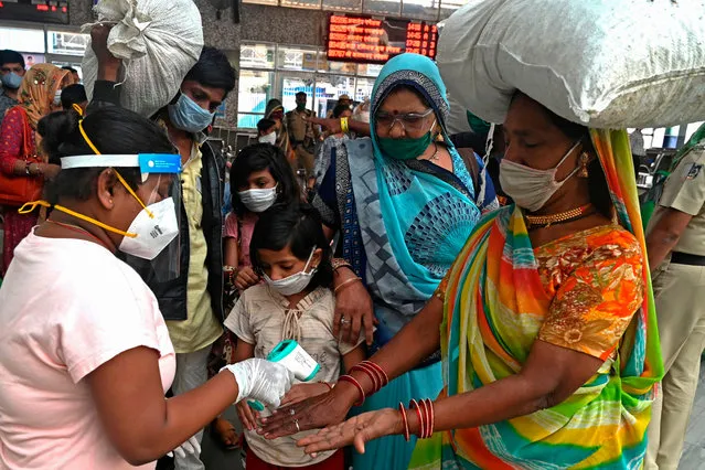 A health worker checks the body temperature of train passengers upon their arrival during the mandatory Covid-19 coronavirus screening at a railway terminus in Mumbai on December 9, 2020. (Photo by Indranil Mukherjee/AFP Photo)