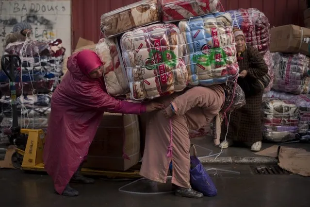 Women porters load bundles onto their back for transport across the El Tarajal boarder separating Morocco and Spain's North African enclave of Ceuta, in Ceuta on December 4, 2014. Unemployment among Ceuta and Melilla's native workforce is more than 30 percent – among the highest rates in Spain. Meanwhile, authorities say some 30,000 Moroccan traders and menial workers cross into each territory every day. (Photo by Jorge Guerrero/AFP Photo)
