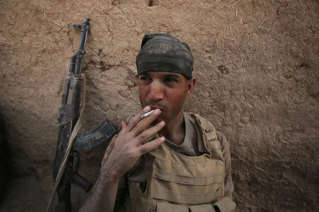 A member of the Iraqi government forces smokes a cigarette as they rest in the village of al-Khuwayn, south of Mosul, after recapturing it from Islamic State (IS) group jihadists on October 23, 2016, in part of an ongoing operation to tighten the noose around Mosul and reclaim the last major Iraqi city under IS control. (Photo by Ahmad Al-Rubaye/AFP Photo)