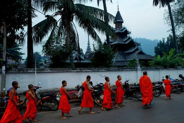 Boys walks for almsgiving early morning after entering the Buddhist novicehood at a temple where they live for one or two months during their school holidays, studying Buddhist scripture, in Mae Hong Son, Thailand, April 15, 2018. (Photo by Jorge Silva/Reuters)