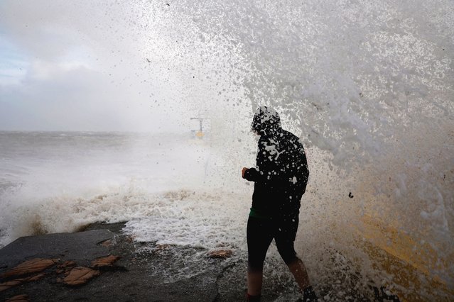 A woman is caught by a large wave at Blackrock diving tower during Storm Amy which brought severe weather, in Galway, Ireland, on October 3, 2025. (Photo by Clodagh Kilcoyne/Reuters)