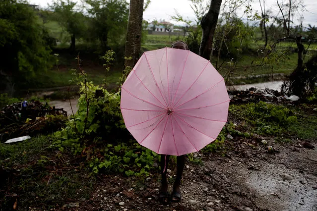 A boy looks above as he hides himself behind an umbrella after Hurricane Matthew in Les Cayes, Haiti, October 21, 2016. (Photo by Andres Martinez Casares/Reuters)