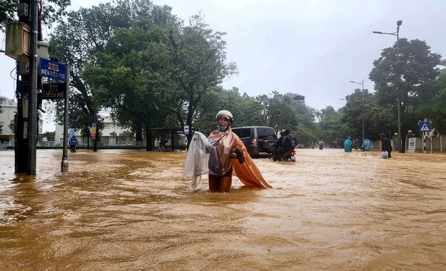 A woman wearing a raincoat wades through a flooded street in Hue on October 28, 2025. The central Vietnamese city of Hue recorded more than a metre of rainfall in a 24-hour period, smashing a national record set over two decades ago, the environment ministry said. (Photo by AFP Photo/Stringer)